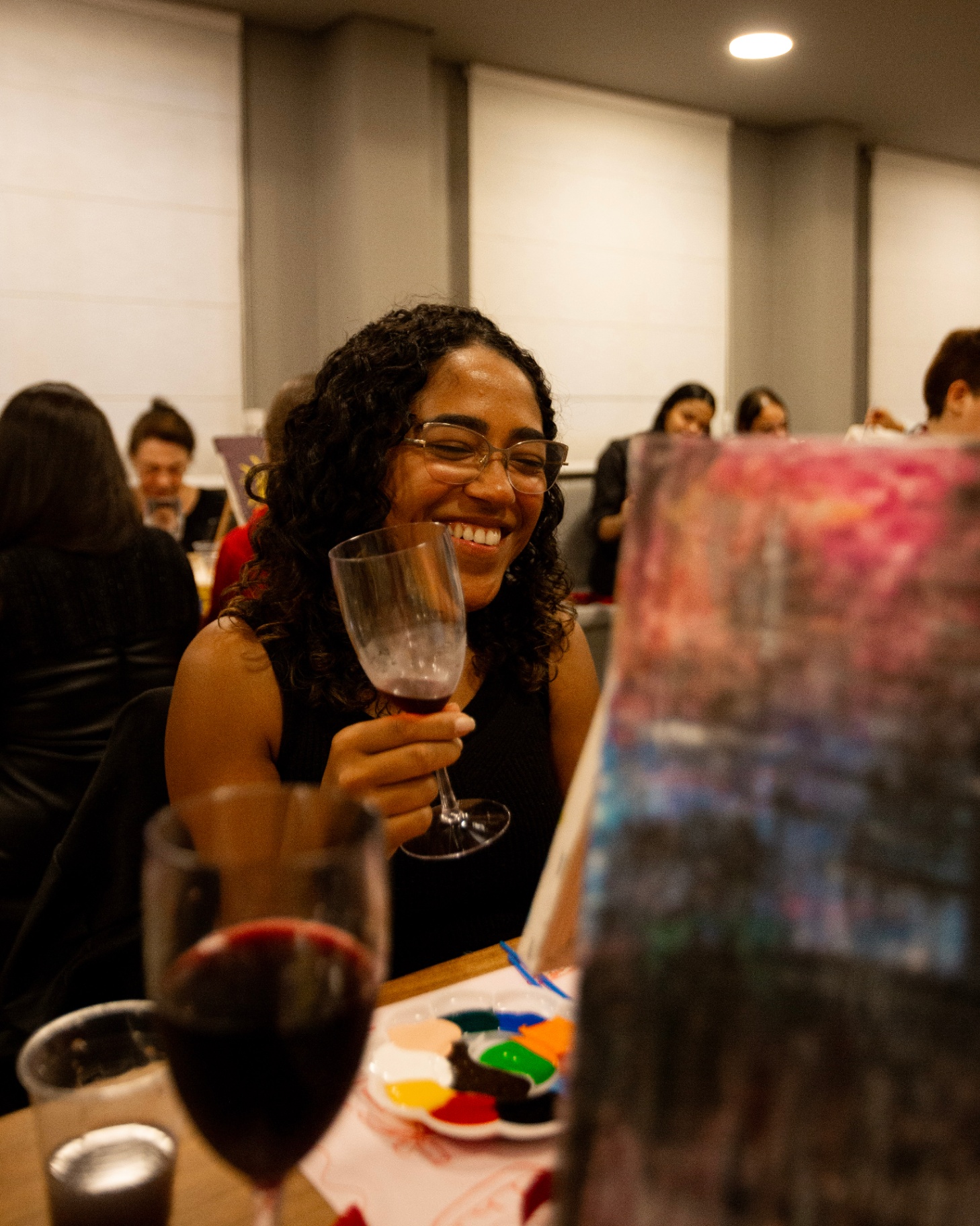 Participante sorrindo com taça de vinho durante o encontro