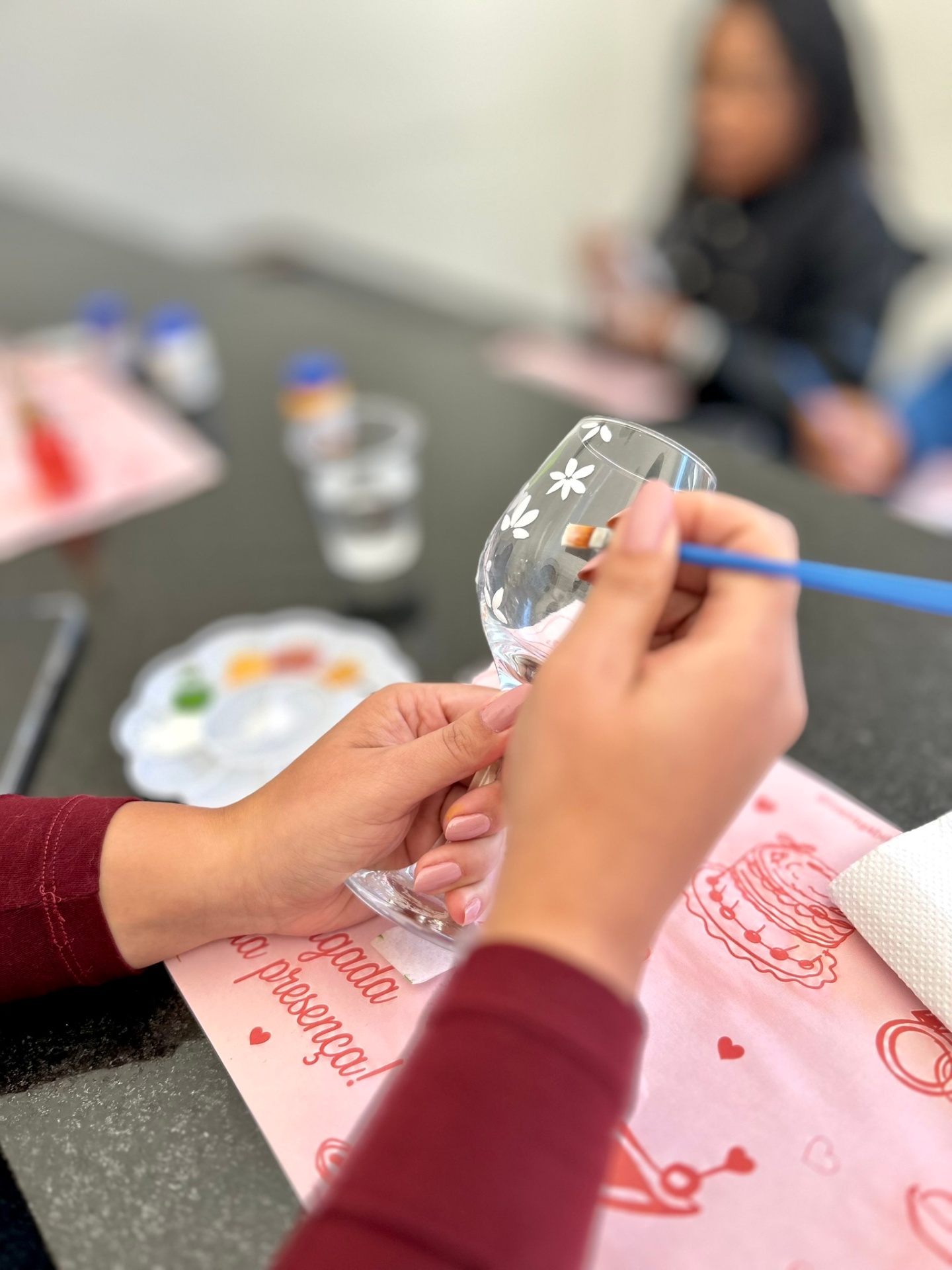 Mãos pintando flores delicadas em taça transparente