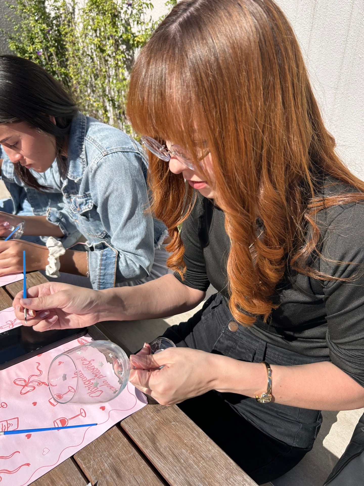 Participante ruiva pintando taça em mesa ao ar livre