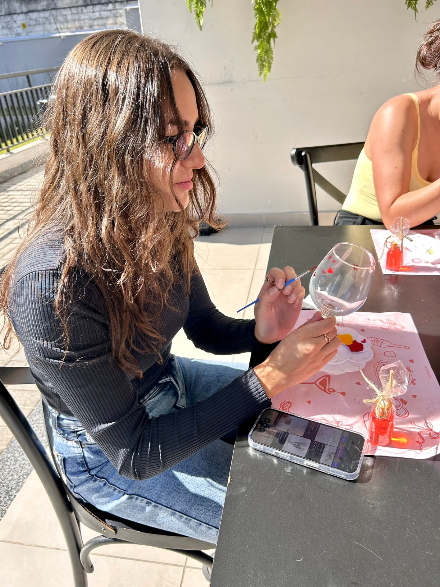 Participante pintando coraçõezinhos em sua taça de vinho